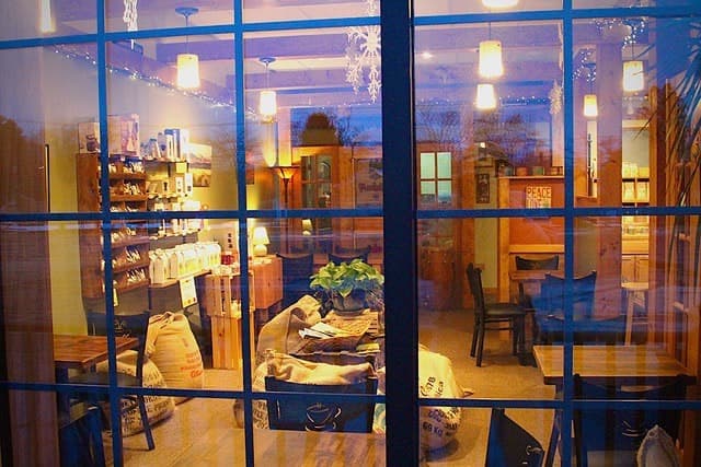 The Lakewood shop window glowing at dusk, warm light and seats inside